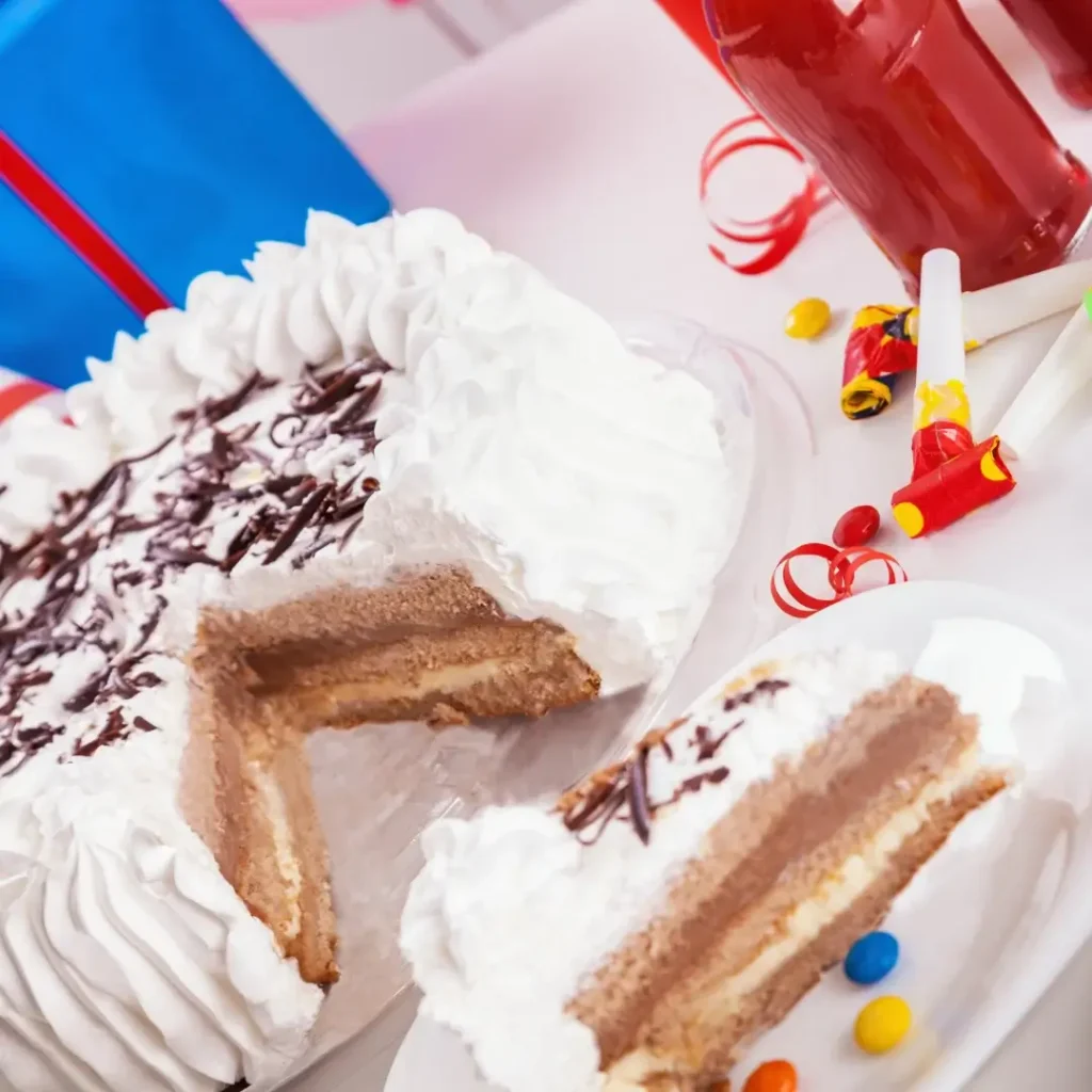 Bolo de duas camadas com cobertura de chantilly e fatia sendo retirada